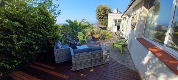 A patio area with wicker furniture, a wooden deck, and a view of the ocean.