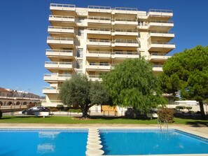 Enjoy a refreshing swim in the pool surrounded by lush greenery and a beautifully maintained lawn.