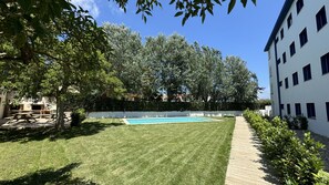 A well-maintained outdoor area with a swimming pool, a grassy lawn, and a wooden deck. - TER 21D close to the beach, WiFI, BBQ (Torroella de Montgri)