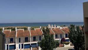 Un quartier résidentiel en bord de mer, avec des bâtiments aux toits de tuiles rouges, un ciel bleu azur et la mer en toile de fond.