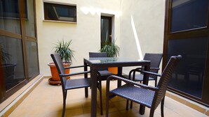 A patio area with a table and chairs, potted plants, and a window.