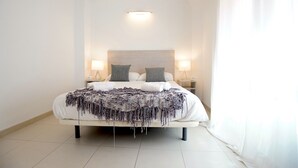 A neatly made bed with a white headboard, two bedside lamps, and a decorative throw blanket.