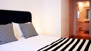 Ein Hotelzimmer mit einem Bett, einer schwarz-weiß gestreiften Tagesdecke und schwarz-weiß gemusterten Kissen.