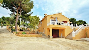 A two-story building with a yellow facade, a balcony with white railings, and a staircase leading to the entrance. - Sofia - holiday home with private swimming pool in Moraira (Teulada)