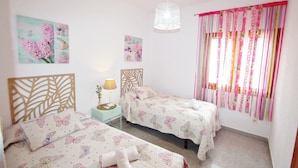 A bedroom with two beds, a wooden headboard, a hanging light fixture, and a window with striped curtains. - Sofia - holiday home with private swimming pool in Moraira (Teulada)