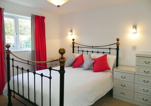 Classic four-poster bed with white bedding and a mix of pillows, complemented by a dresser and bedside table.
