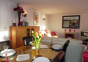 Enjoy meals with family and friends at the dining table, surrounded by a comfortable living room with a fireplace and a beautiful piece of artwork.
