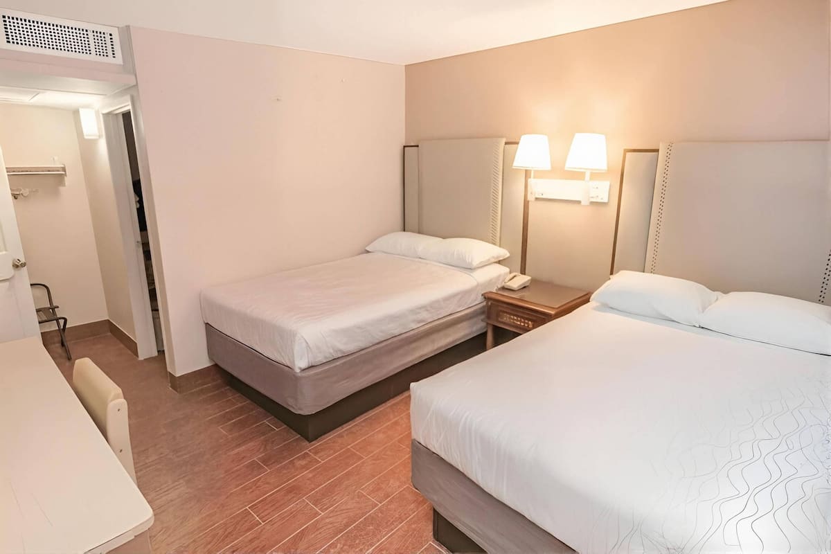 Une chambre d’hôtel avec deux lits, un bureau et une chaise.