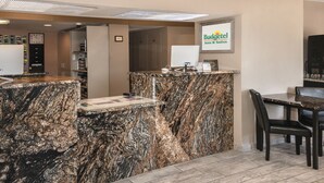 A reception desk with a marble top, a clock, and a sign for Budgettel Inns & Suites.