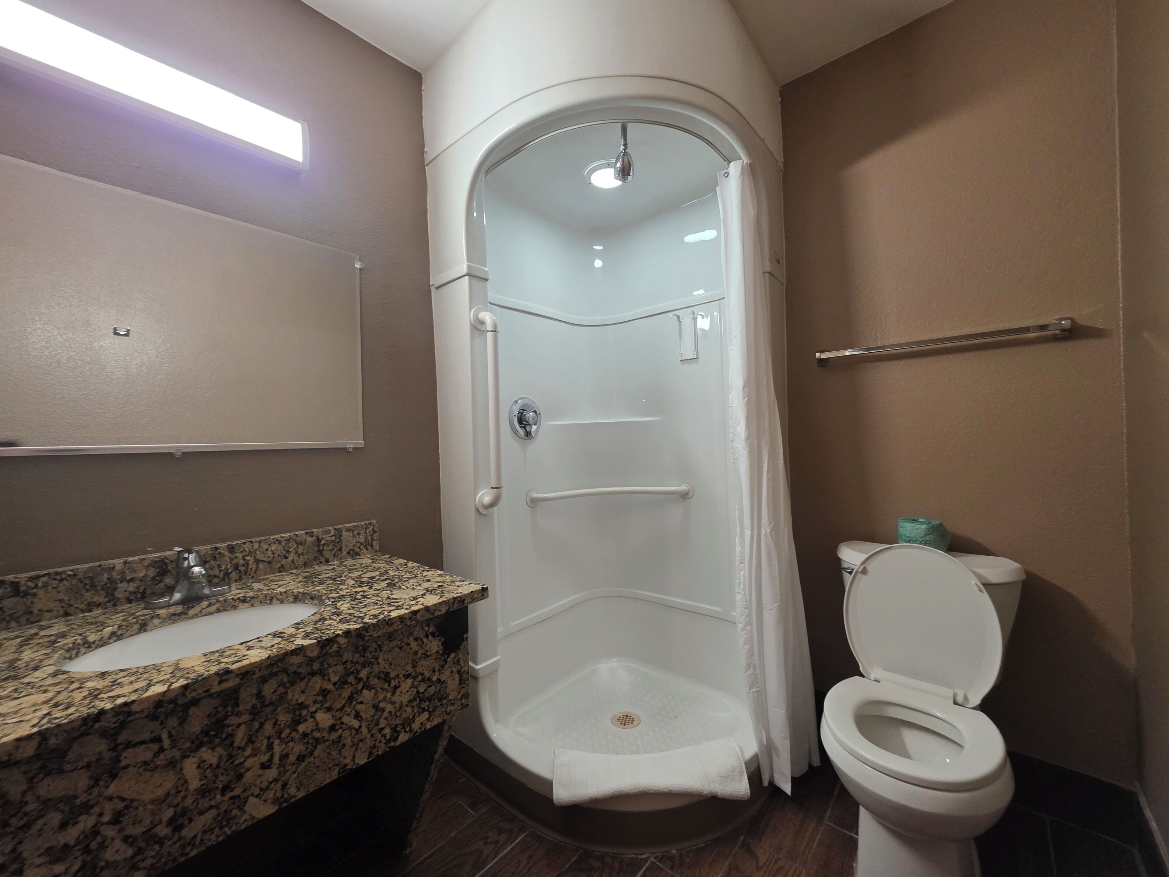 Baño con ducha, inodoro y lavabo de encimera de granito.