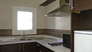 A kitchen with a window, stainless steel sink, double oven, and dark wooden cabinets. - Apartments with terrace and communal pool. Ref. Tropik-46 (Estartit)