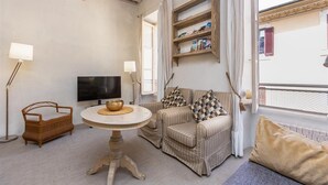 Una sala de estar con un sofá, un televisor, una mesa con un tazón y una estantería.