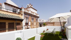 A courtyard with artificial grass, white outdoor furniture, and a table with a drink and a small plant. - San Francisco Penthouse Studio (Sevilla)
