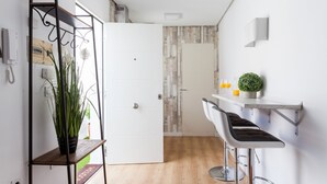 A modern kitchen with a wooden countertop, two bar stools, and a potted plant. - San Francisco Penthouse Studio (Sevilla)