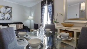 A modern dining area with a glass table, four white bowls, and a pitcher.