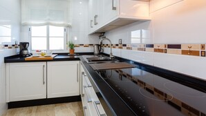 A modern kitchen with white cabinets, a black countertop, and a black stovetop.