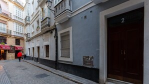 A narrow cobblestone street with buildings on either side, featuring a large dark wooden door on the right and a sign with the number "2" above it.
