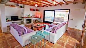Ein Wohnzimmer mit Kamin, weißen Sofas, einem Glastisch und einem Fernseher.