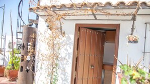Una puerta de madera con un pestillo metálico, una pared blanca y un tejado de baldosas.