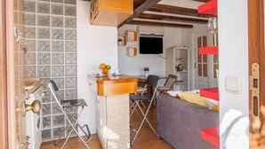 Un espacio habitable compacto con kitchenette, comedor y zona de estar.