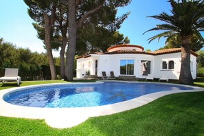 Una casa con piscina, rodeada de árboles y un césped cuidado.