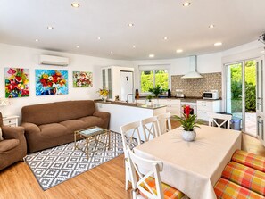 A modern kitchen with white cabinets, a microwave, and a window overlooking a garden.