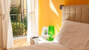 Un dormitorio con cama, mesita de noche, lámpara verde y ventana con cortinas.