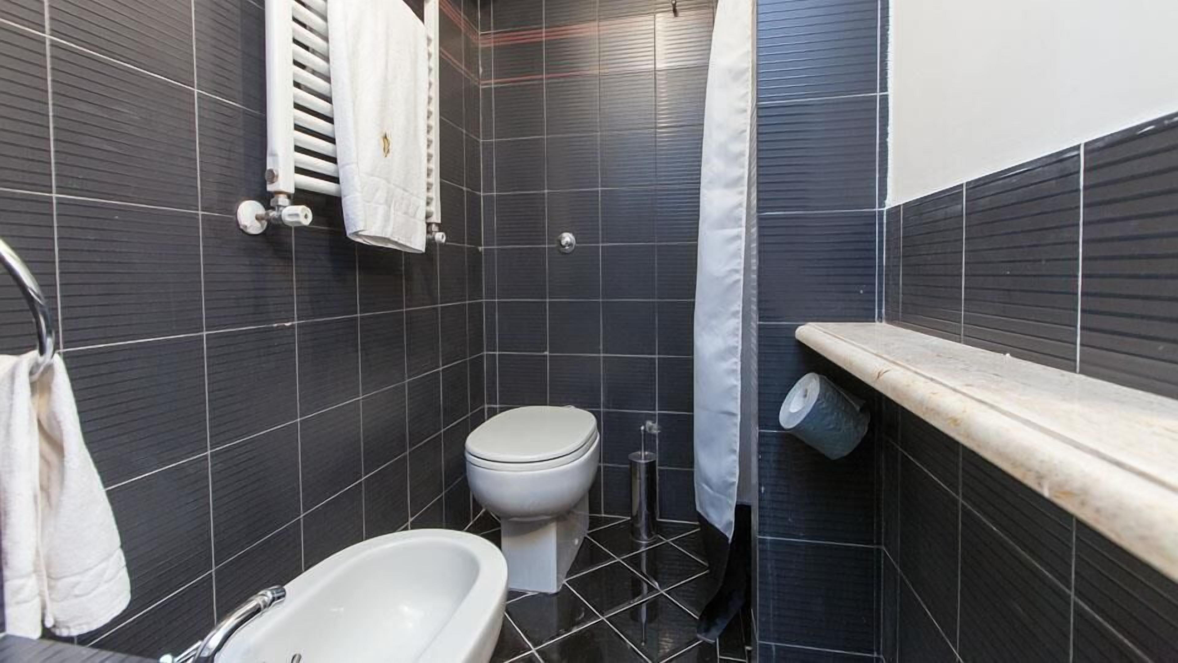 A small bathroom with a toilet, a bathtub, and a towel rack.