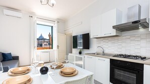 A modern kitchen with white cabinets, a gas stove, and a view of a building through an open door. - Your own private view over St.Peter! (Rome)