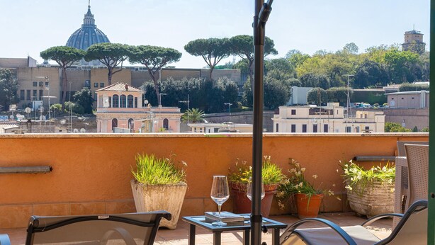 A rooftop terrace with outdoor seating, potted plants, and a view of historic buildings. - Your own private view over St.Peter! (Rome)