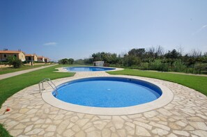 A swimming pool with a stone border, surrounded by a well-maintained lawn and a pathway. - Daró 3D 37 - A/C, pool and 150m from the beach (Torroella de Montgri)