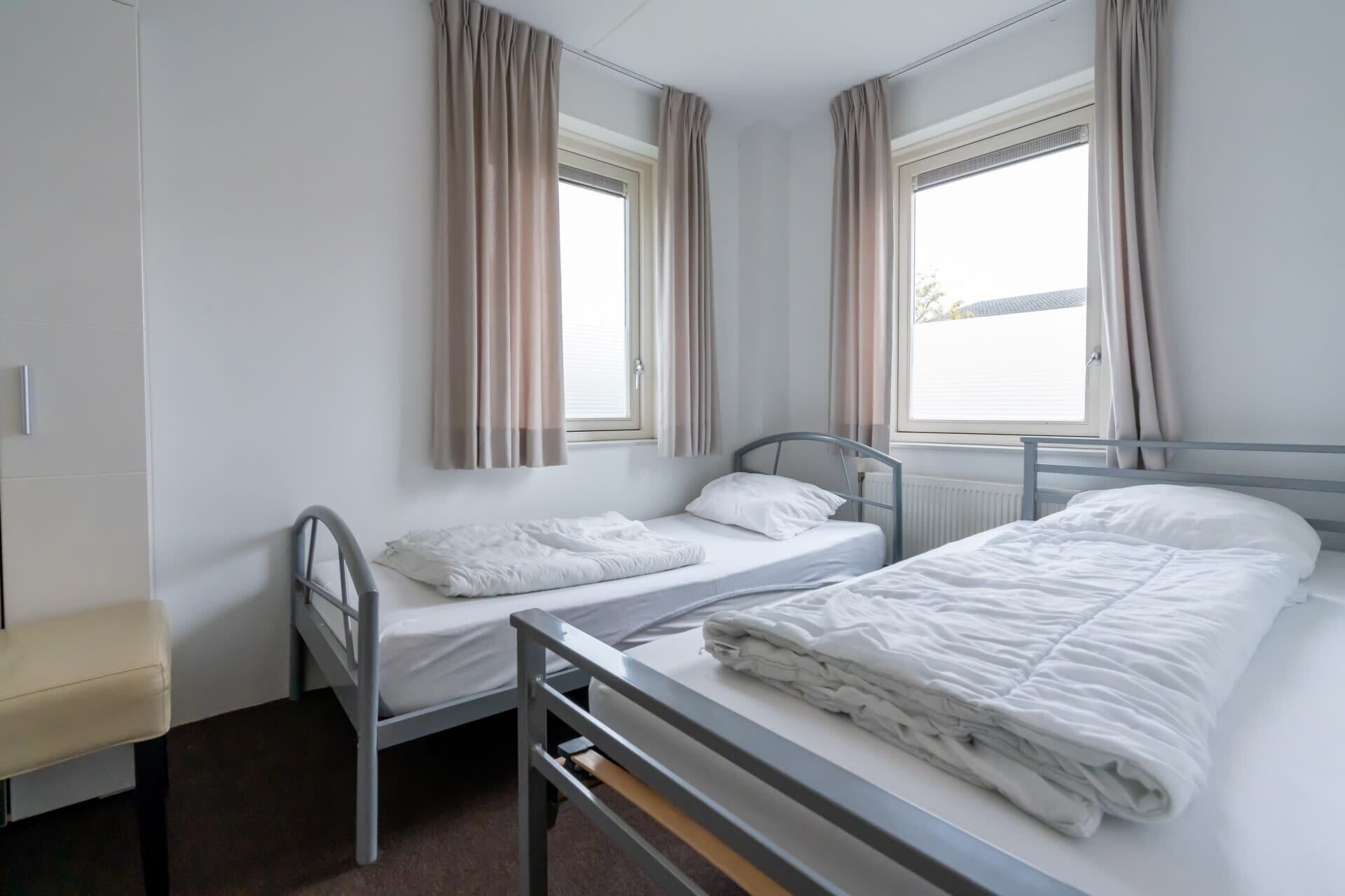 A twin room with two beds, a window, and a radiator.