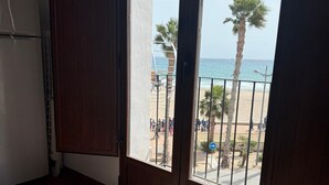 A room with a view of a beach, a patterned floor, and a door leading outside.