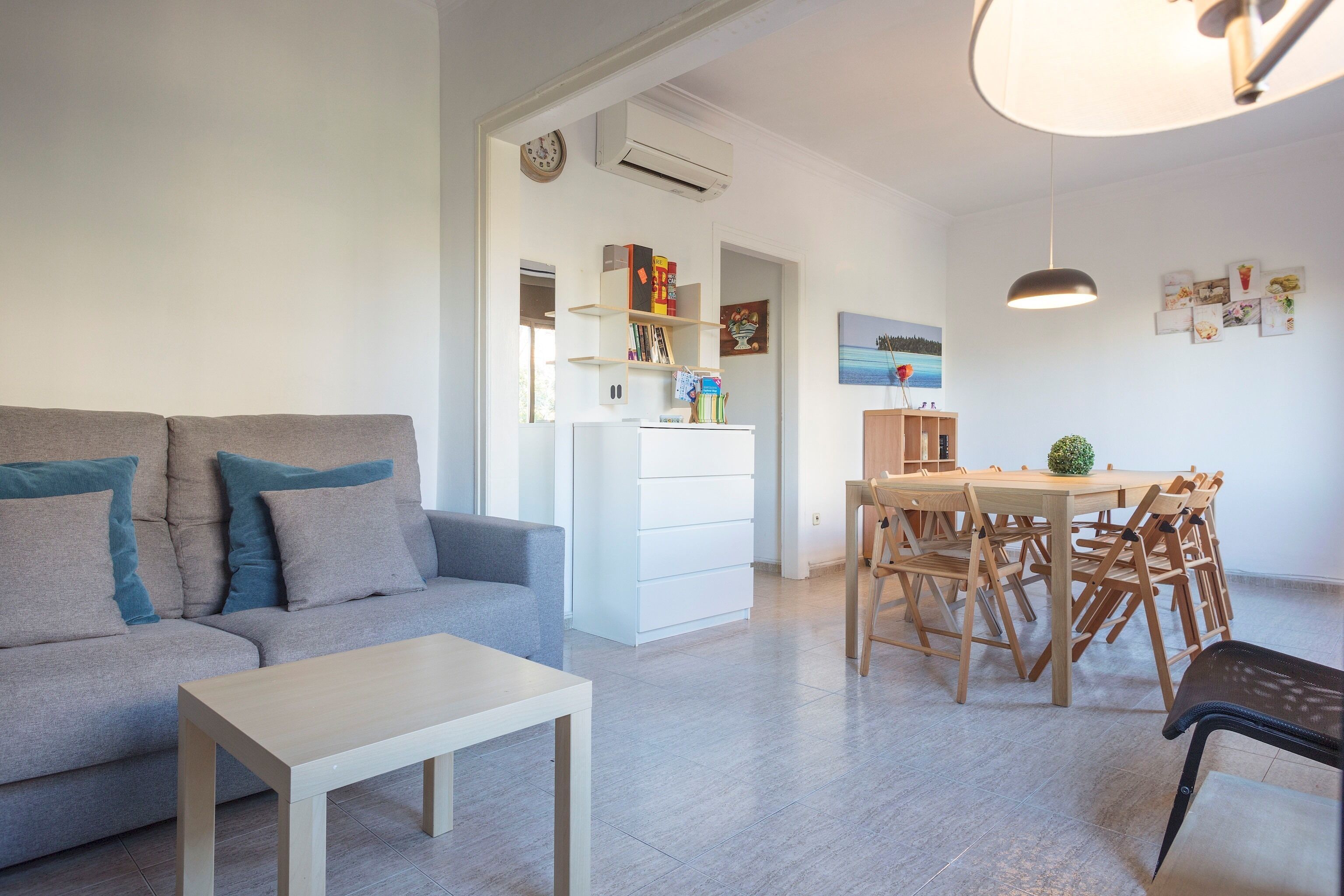 A modern living room with a sofa, a dining table with chairs, and a small table.