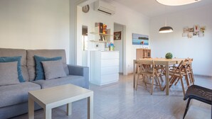 Una sala de estar moderna con un sofá, una mesa de comedor con sillas y una mesita.