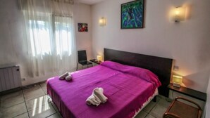 Une chambre à coucher avec un grand lit, une chaise, un bureau et un tableau accroché au mur.
