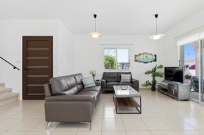 Ein modernes Wohnzimmer mit Sofa, Couchtisch, Fernseher und einem Balkon mit Blick.