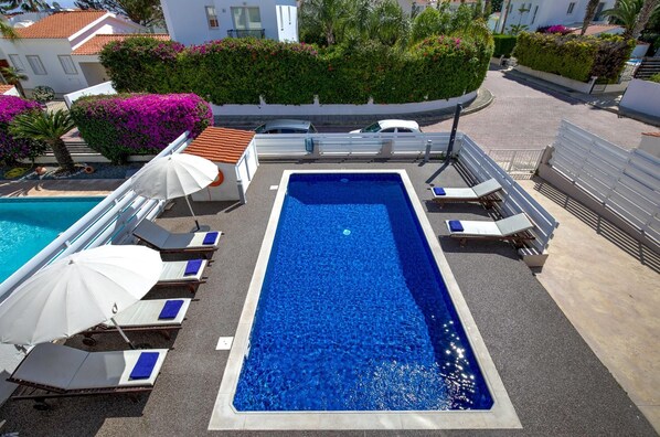 Une piscine sur le toit, avec des chaises longues et des parasols.