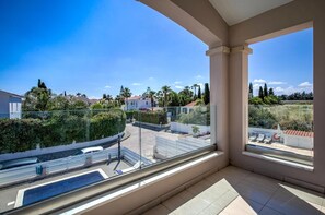 A balcony with a clear view of a residential area, including houses and greenery.