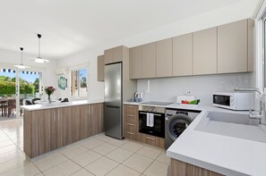 A modern kitchen with a central island, built-in appliances, and a view of the outdoor area.