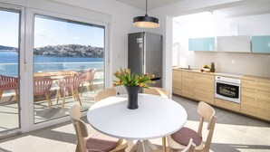 Et moderne køkken med havudsigt, et spiseområde med et rundt bord og stole, og et køleskab med en klistermærke.