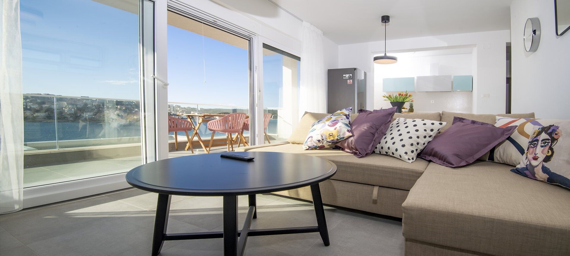 Un salon moderne avec un canapé, une table ronde et un balcon offrant une vue agréable.