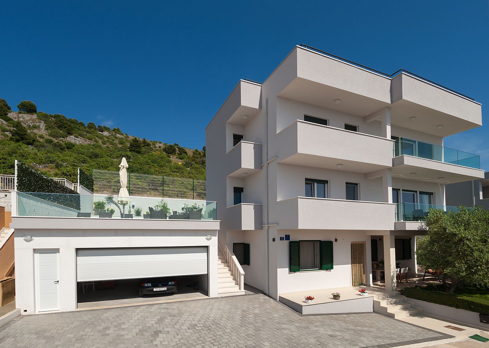 Ein modernes, mehrstöckiges Gebäude mit Garage, Außenbereich und einer Statue im Hintergrund.