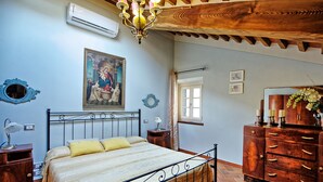 A bedroom with a bed, a wooden dresser, a mirror, and a painting on the wall. - Flavia 1 - Vacation Rental with swimming pool in Lucca (Lucca)