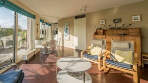 Amplia sala de estar con un ventanal grande, comedor y una zona de estar acogedora con chimenea.