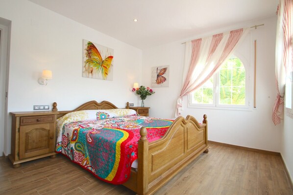 A bedroom with a wooden bed, a nightstand, a dresser, and a window with curtains. - GALLO Gran villa en playa, piscina y wifi gratis (Miami Playa)