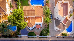 An aerial view of a residential area with two swimming pools, a large tree, and a well-maintained garden. - GALLO Gran villa en playa, piscina y wifi gratis (Miami Playa)