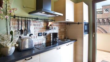 Eine kompakte Küche mit Ziegelrückwand, einem Toaster, einer Kaffeemaschine und hängenden Küchenutensilien.