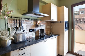 A compact kitchen with a brick backsplash, a toaster, a coffee maker, and hanging utensils.