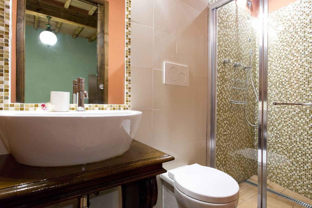 Ein Badezimmer mit einem großen, weißen Waschbecken, einer Toilette und einem Duschbereich mit Glaswand.